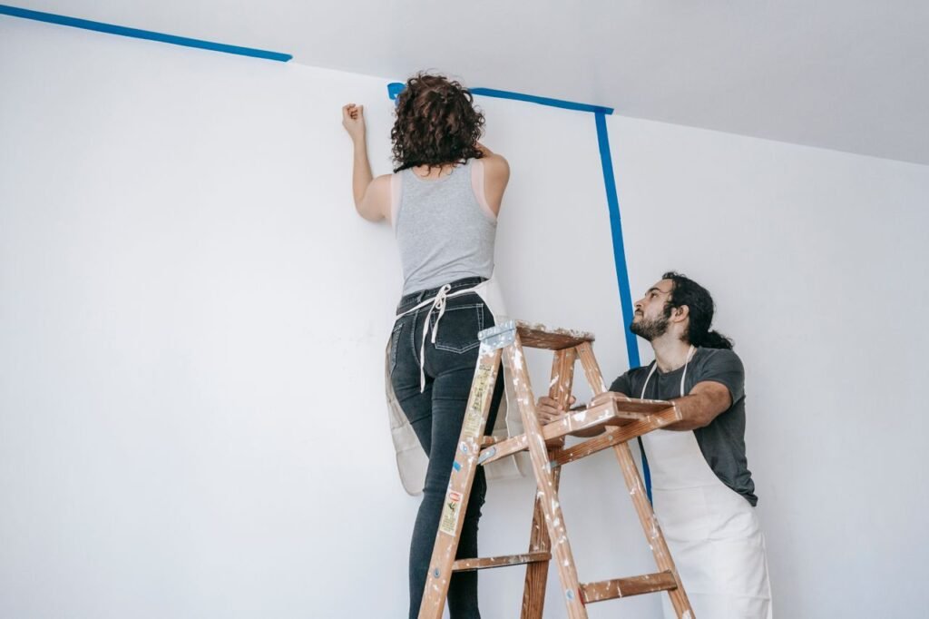 Save Time and Money: Repairs You Can Skip When Selling Your Home A couple collaborates on home renovation with paint and ladder.