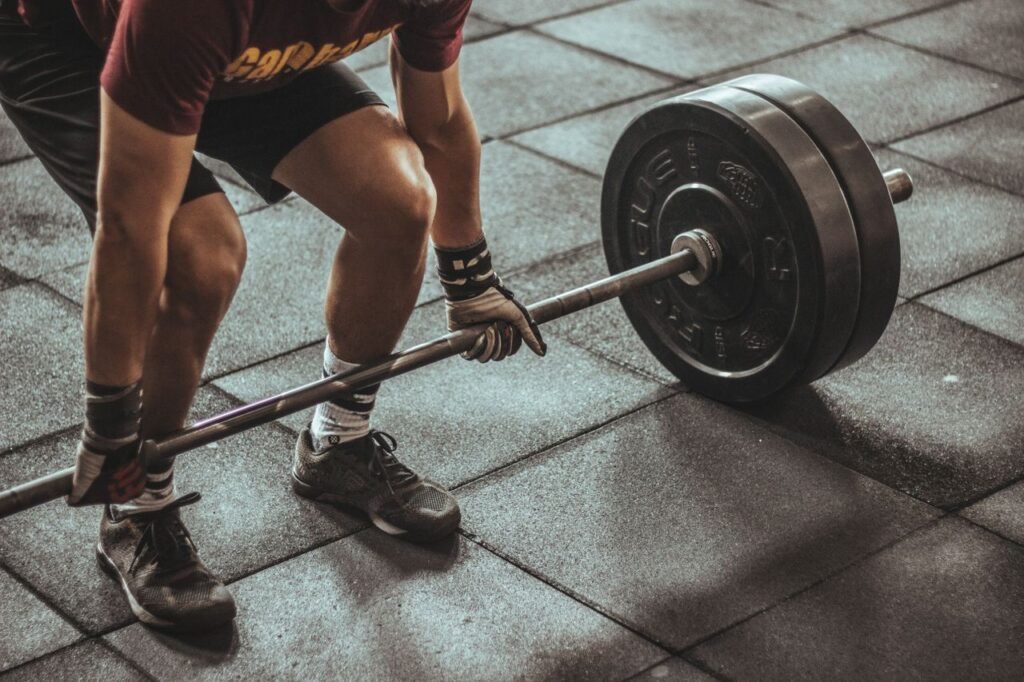 The Power of Consistency: Lessons from Jeremy Herider on Success in Fitness, Business, and Life A focused weightlifter prepares to lift a heavy barbell in an indoor gym setting.